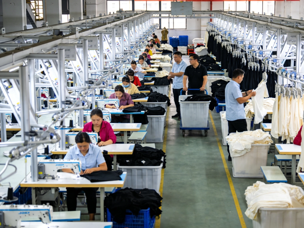 Quality control inspector examining stitching details on wholesale girls' dresses at a reliable children's apparel manufacturer factory.