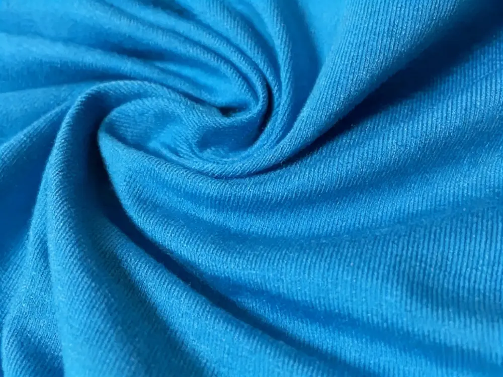 Close-up texture of buttery soft pink modal fabric showing silky drape