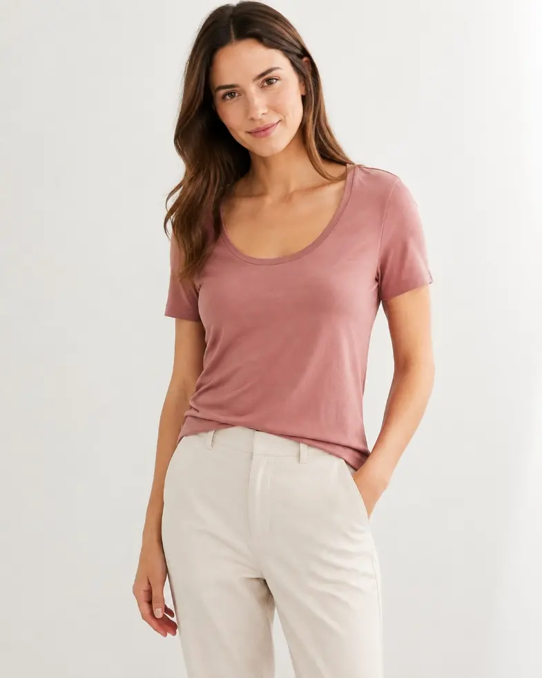 Model wearing a dusty rose scoop-neck T-shirt with a wide rounded neckline