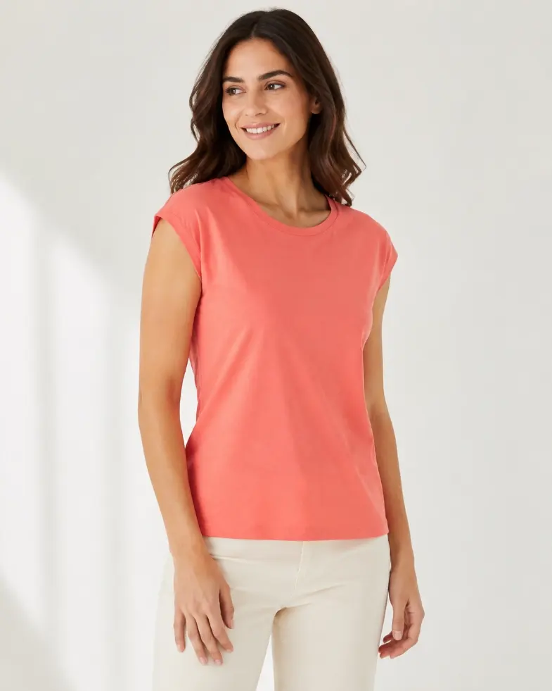 Model wearing a coral cap-sleeve T-shirt with sleeves covering the shoulder edge