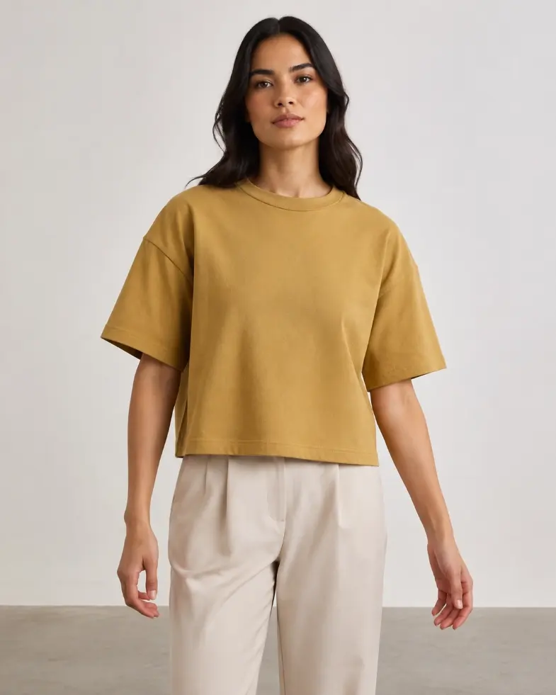 Model wearing a mustard boxy T-shirt with a wide body and shorter length